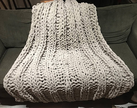 Hand-knitted chunky chenille yarn blanket in cream white for sofa decor.